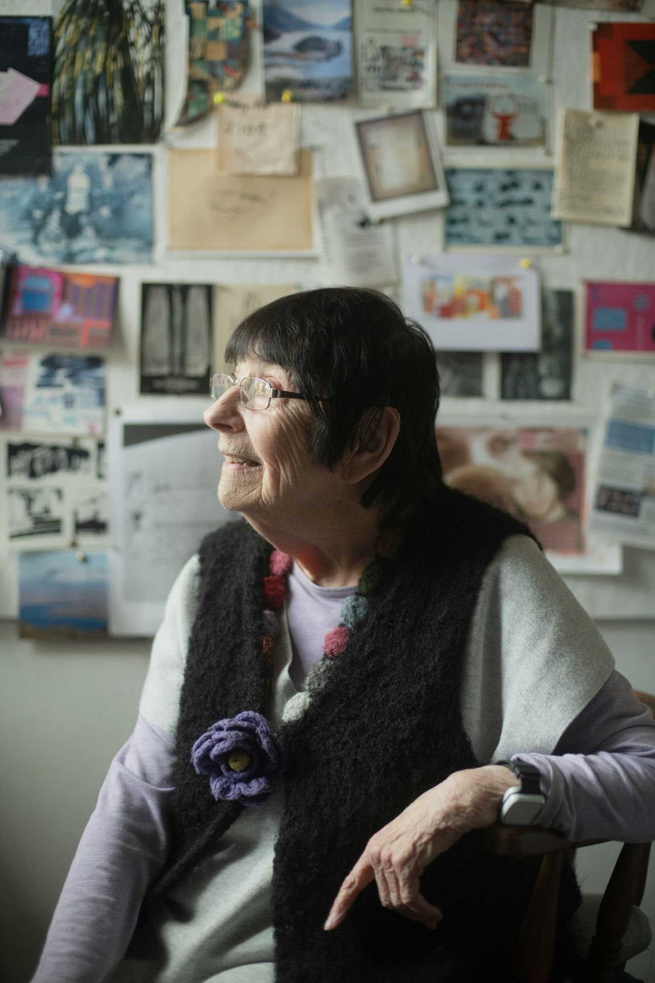 A woman sitting in a chair in front of a wall with pictures on it